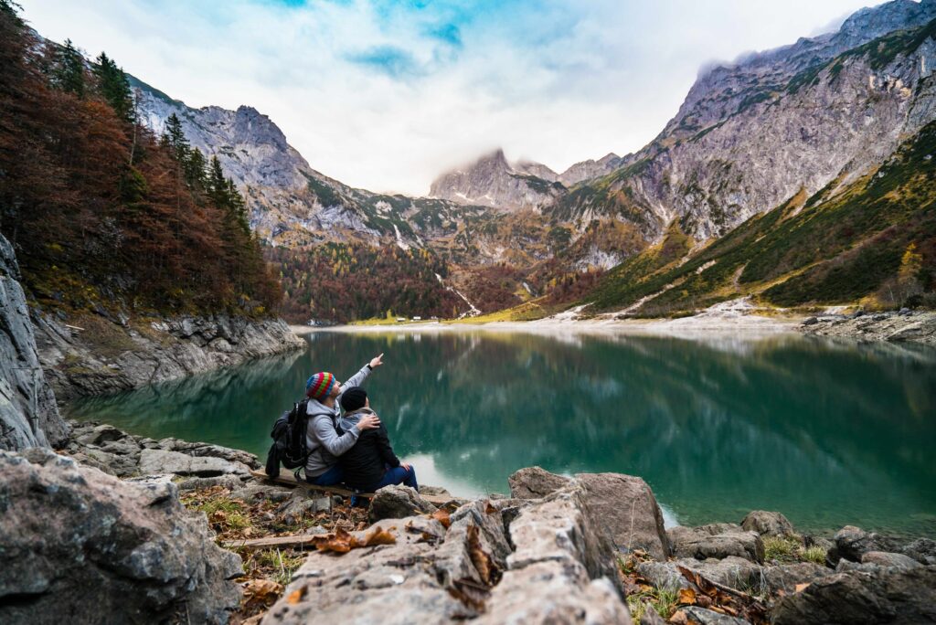 A couple at the bank of a mountain lake pointing out something in the distance meant to evoke a feeling of seeing past limits